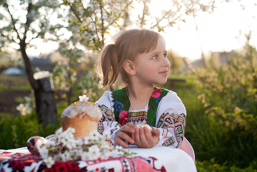 Young girl in Ukrainian national dress is based on a table with decorative Easter eggs