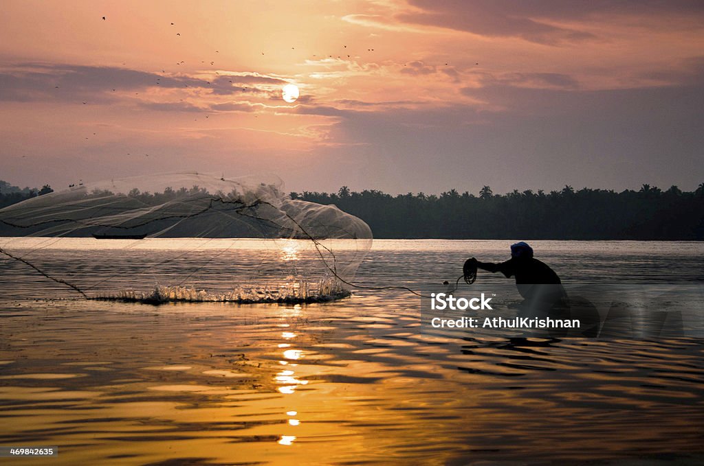 Fisherman casting a fishing net Fisherman casting his net into a river. An early morning scene from Kerala, India. Vypeen Island Stock Photo