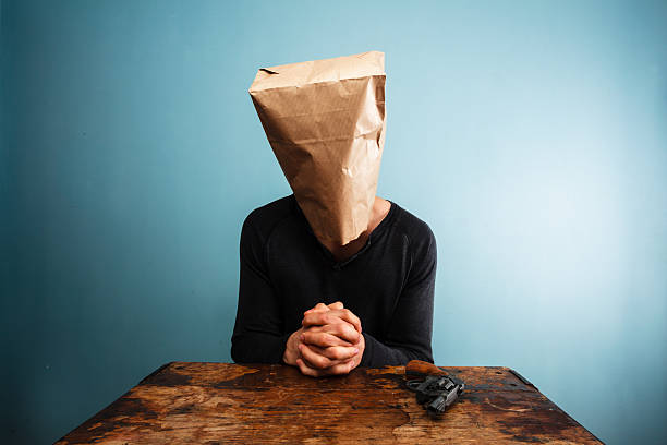 istock Praying man with revolver and a bag over head 469843813