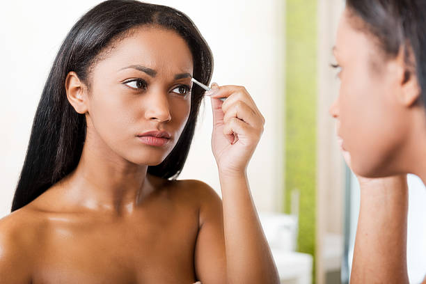 istock Woman tweezing eyebrows. 469846464
