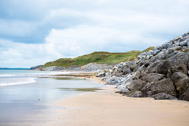 A lone female standing in front of the ocean on a grey moody day on the coast of the Aran Islands, located just off Galway and Doolin on the Irish mainland