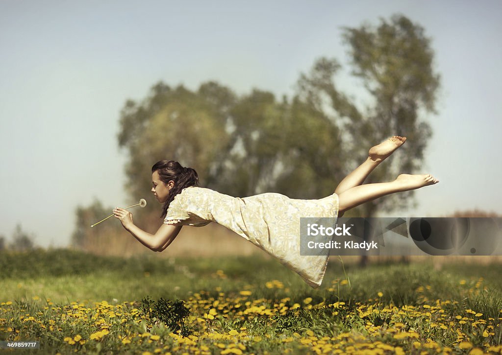 Girl flies over a field. Girl in pajamas night flying over the field and smelling dandelions. Surrealism Stock Photo