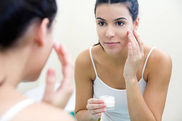 istock Body care. Woman applying cream on face 469859883