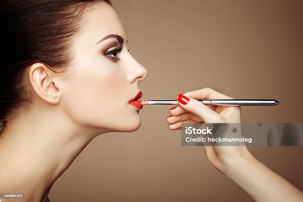 Close-up of makeup artist hand applying lipstick on model Makeup artist applies lipstick. Beautiful woman face. Perfect makeup 2015 Stock Photo