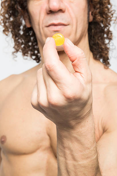 homme prenant la pilule - vitamin pill vertical high key photographic effects photos et images de collection