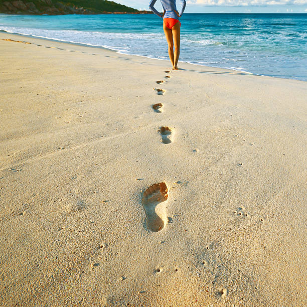 istock Woman at beautiful beach. Focus on footprints. 469867928