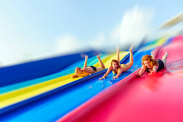 amusement park funny friends in water park laughing on water slide. holiday camp stock pictures, royalty-free photos & images