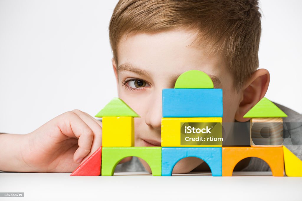 Portrait of a boy hiding behind house made of wooden blocks 2015 Stock Photo