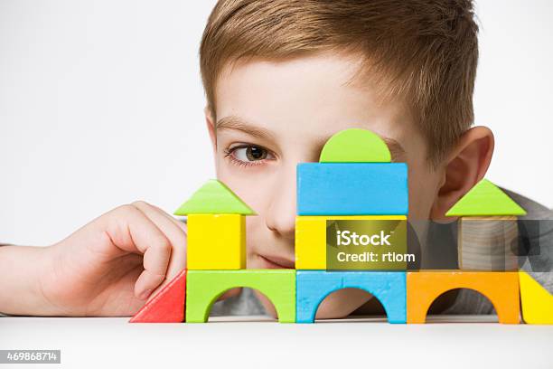 Portrait Of A Boy Hiding Behind House Made Of Wooden Blocks Stock Photo - Download Image Now