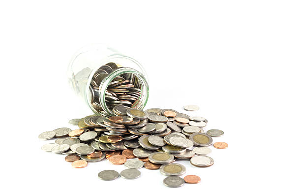 istock Isolated coins spilling from a money jar 469868976