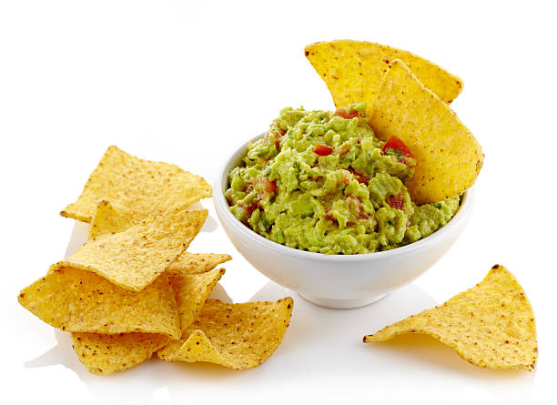 Guacamole in a bowl and tortilla chips Bowl of guacamole dip and nachos isolated on white background guacamole photos stock pictures, royalty-free photos & images