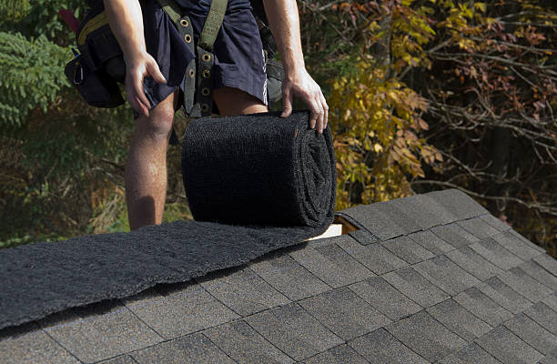 Manic shorts on shingled roof installing a ridge vent. A roofer rolls out ridge vent material used on the peak of new residential house construction. mountain ridge stock pictures, royalty-free photos & images