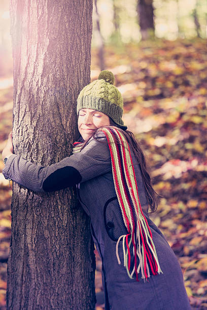 istock woman hugging a tree in autumn 469874719