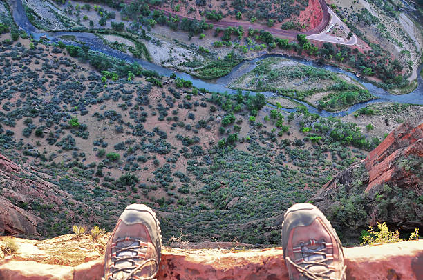 Man's feet on the edge of rock cliff stock photo