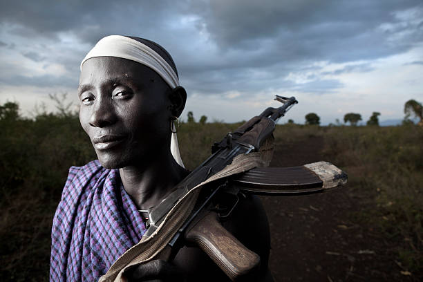 Young African man from Karo tribe posing with AK-47 / Kalashnikov and mobile phone - Ethiopia, East Africa. The Karo tribe is a tribe that lives in the southwestern region of the Omo Valley near Kenya, Africa. They are largely pastoralists.