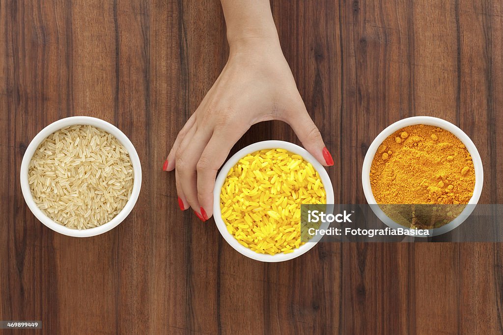 Making yellow rice Hand holding bowl with yellow dyed rice and two others with the ingredients used to make it Ground - Culinary Stock Photo