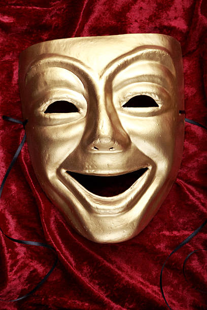 A bright gold comedy mask on a red fabric Comedy mask on red velvet tragicomedy stock pictures, royalty-free photos & images