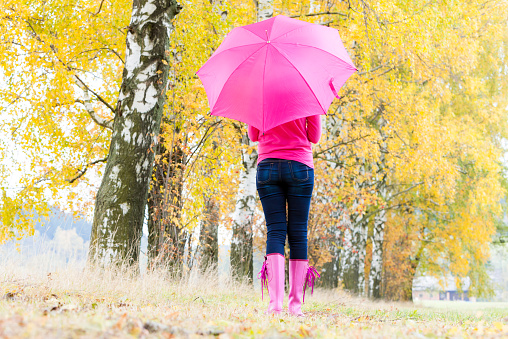 woman wearing rubber boots with umbrella in autumnal naturewoman wearing rubber boots with umbrella in autumnal nature