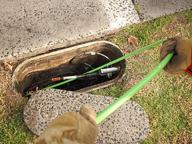 Hobart, Australia - April 11, 2015: Installation of  a green Nylon jacketed 72 fiber optic ribbon cable in a cable duct through a roadside communications pit, used for the National Broadband Network in Australia.   