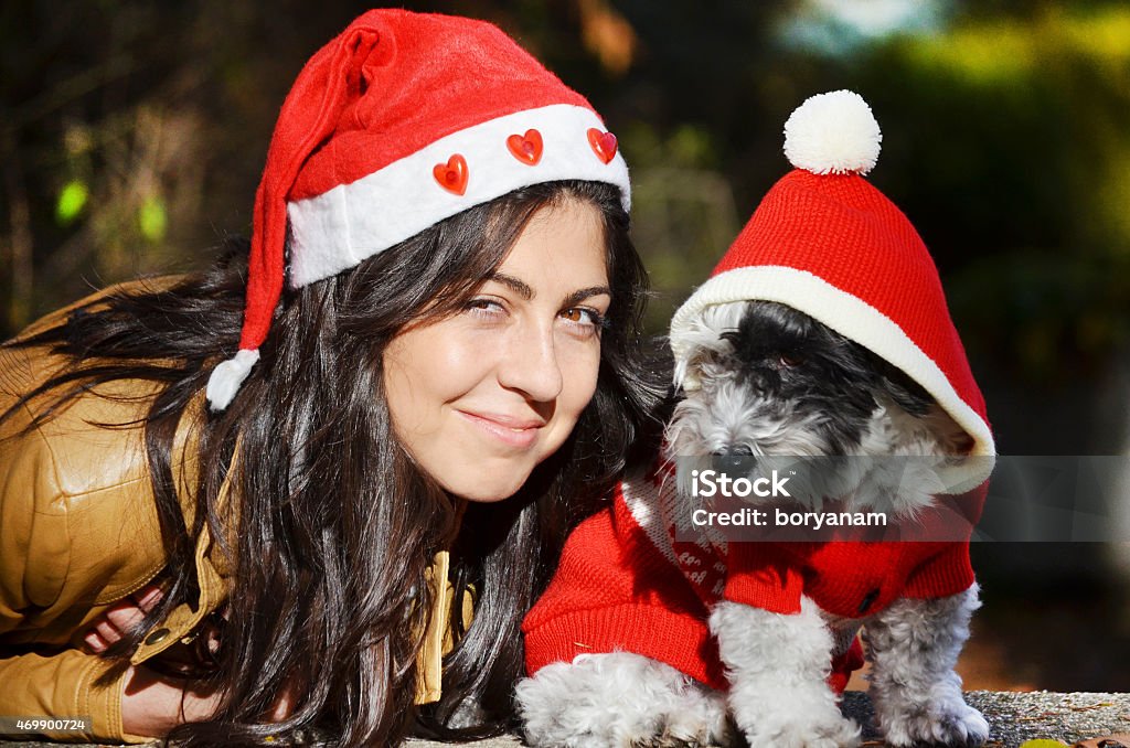 woman and dog with red christmas hats beautiful woman with red christmas hat hugging her white dog 2015 Stock Photo