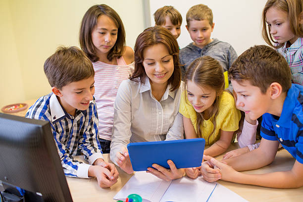 istock group of kids with teacher and tablet pc at school 469901498