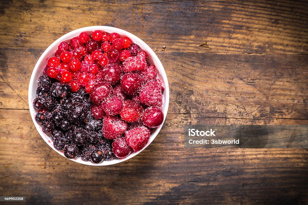 frozen berries in plate on wooden background frozen berries in white plate on wooden background with empty copy space 2015 Stock Photo