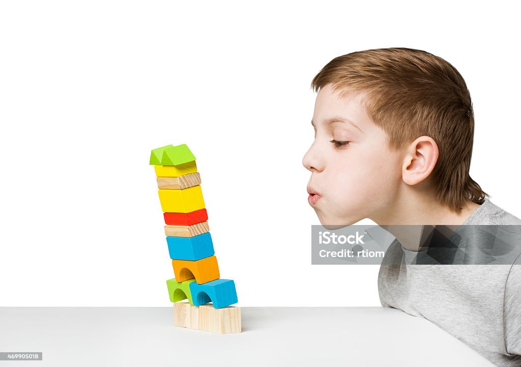 Portrait of a boy blowing on falling house Portrait of a boy blowing on falling house made of wooden blocks Child Stock Photo