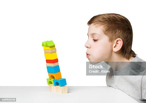 Portrait Of A Boy Blowing On Falling House Stock Photo - Download Image Now - Child, Falling, Toy
