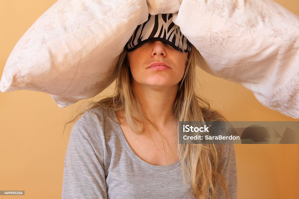 Young women with pillow Sleepy young women with pillow and sleeping eye mask still on. Hangover Stock Photo