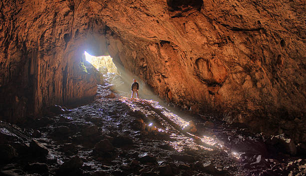 istock big cave with small human and sun rays in it 469906464