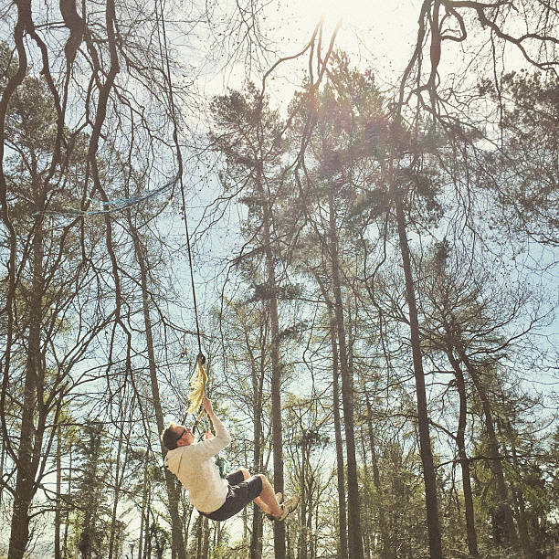 istock Man rope swinging from the tree in the woods, England 469907016