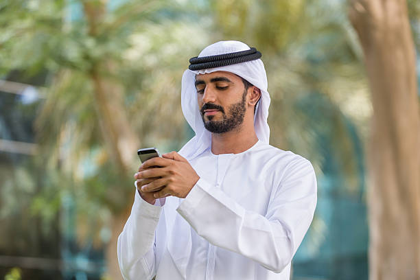 UAE National in a park using smart phone stock photo