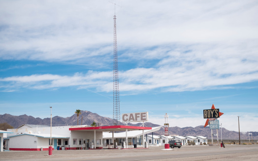 Amboy, United States - February 7, 2014: Partially abondoned tourist stop on the old Route 66 in the Mohave desert in California, about 50 miles north of Twentynine Palms.  The gas station is still in operation and the cafe only sells cold drinks.  Behind the cafe sign is a motel office and a row of small, white buildings that are part of the abandoned motel.  The iconic \