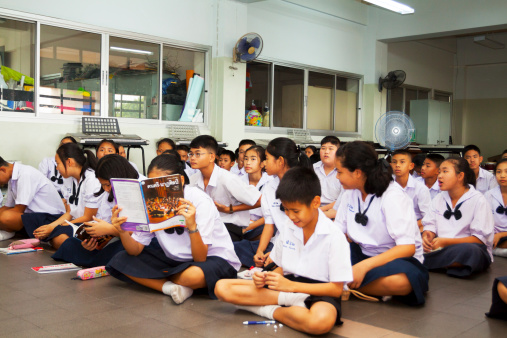 Bangkok, Thailand - February, 6th 2014: Scene and capture of Thai students sitting on floor in classroom during lesson. Classroom is in Satri Wittaya 2 School, Ladprao. Students are listening teacher out of capture.
