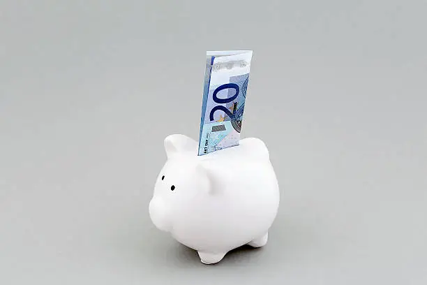 A white piggy bank with European currency (20 Euros).