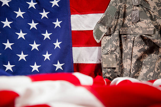 istock U.S.A. military uniform hangs beside American flags. 469908940