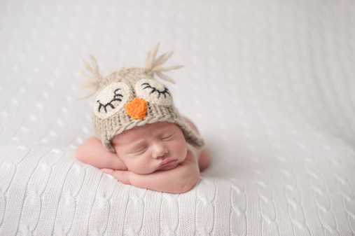 A newborn sleeping in a knit hat.