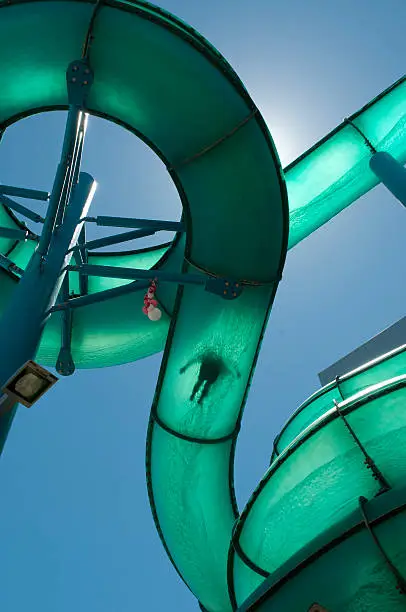 A Person sliding down a waterslide with the sun directly behind