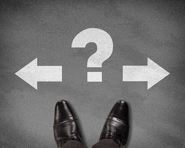 istock Shoes standing on asphalt road with two arrows and question 469909330