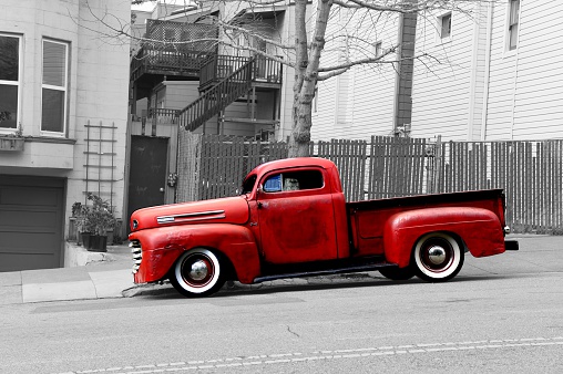 This old and dented, rusted and red Ford Pick-Up in front of  black and white house front adds a vintage touch to any set-up. The picture was taken in 2011 in the steep streets of San Francisco, which is why the car is positioned in a sloped angle.