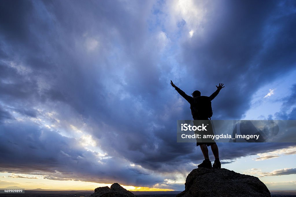 silhouette man with arms raised into sunset sky landscape sunset sky silhouette of anonymous happy man standing with arms spread wide in the sandia mountains of albuquerque, new mexico. horizontal composition with copy space. Achievement Stock Photo