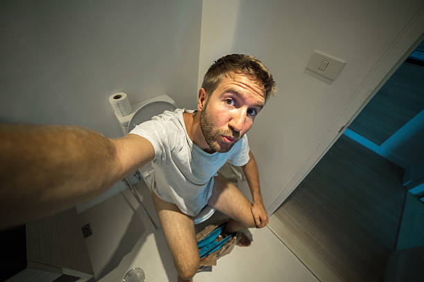 A stock photo of two men, short and tall, standing at urinals in a bathroom as they size each other up.