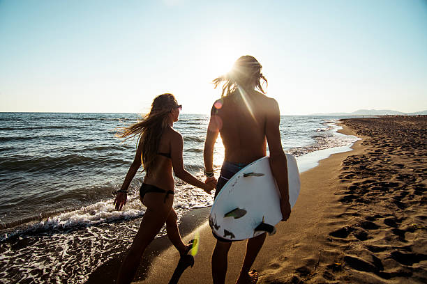 istock Long-haired couple with surfboard walking on the beach 469911254