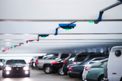 Parked cars in the public underground garage, and indicator lights on the ceilings.