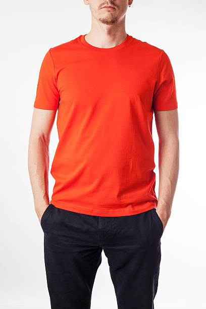 Young man in orange shirt with his hands in his pockets