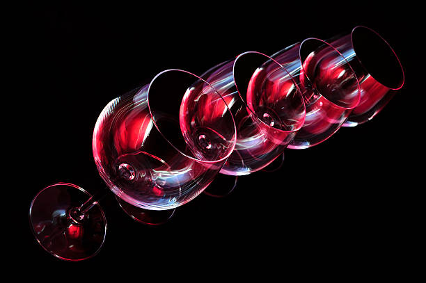 Wine glasses lit by red, blue, lilac nightclub party lights on black background