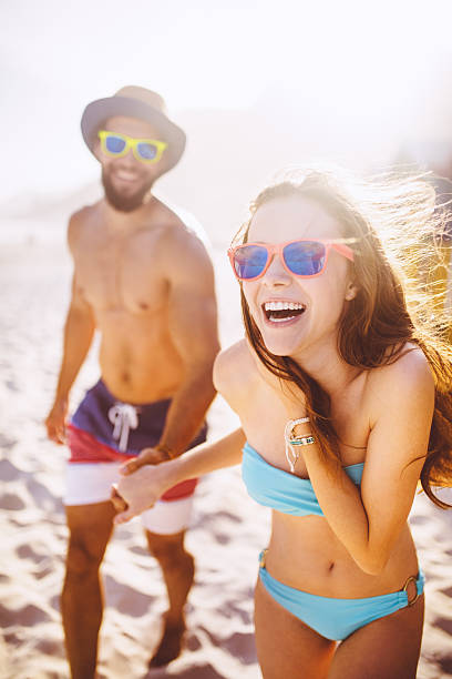 istock Couple laughing and holding hands at the beach 469922108