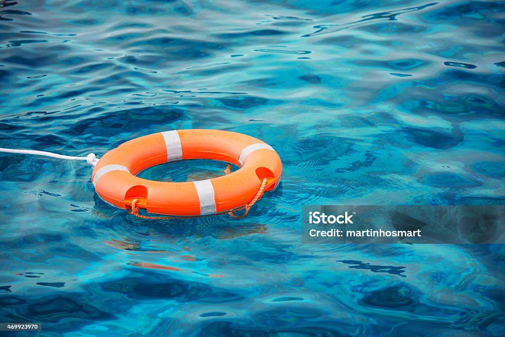 Lifebuoy resting on top of blue waters Lifebuoy in a stormy blue sea Life Belt Stock Photo