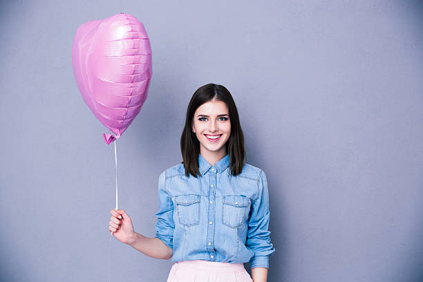 istock Smiling woman holding balloon and looking at camera 469928054