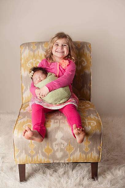 istock Big Sister Holding Newborn Sibling 469932135
